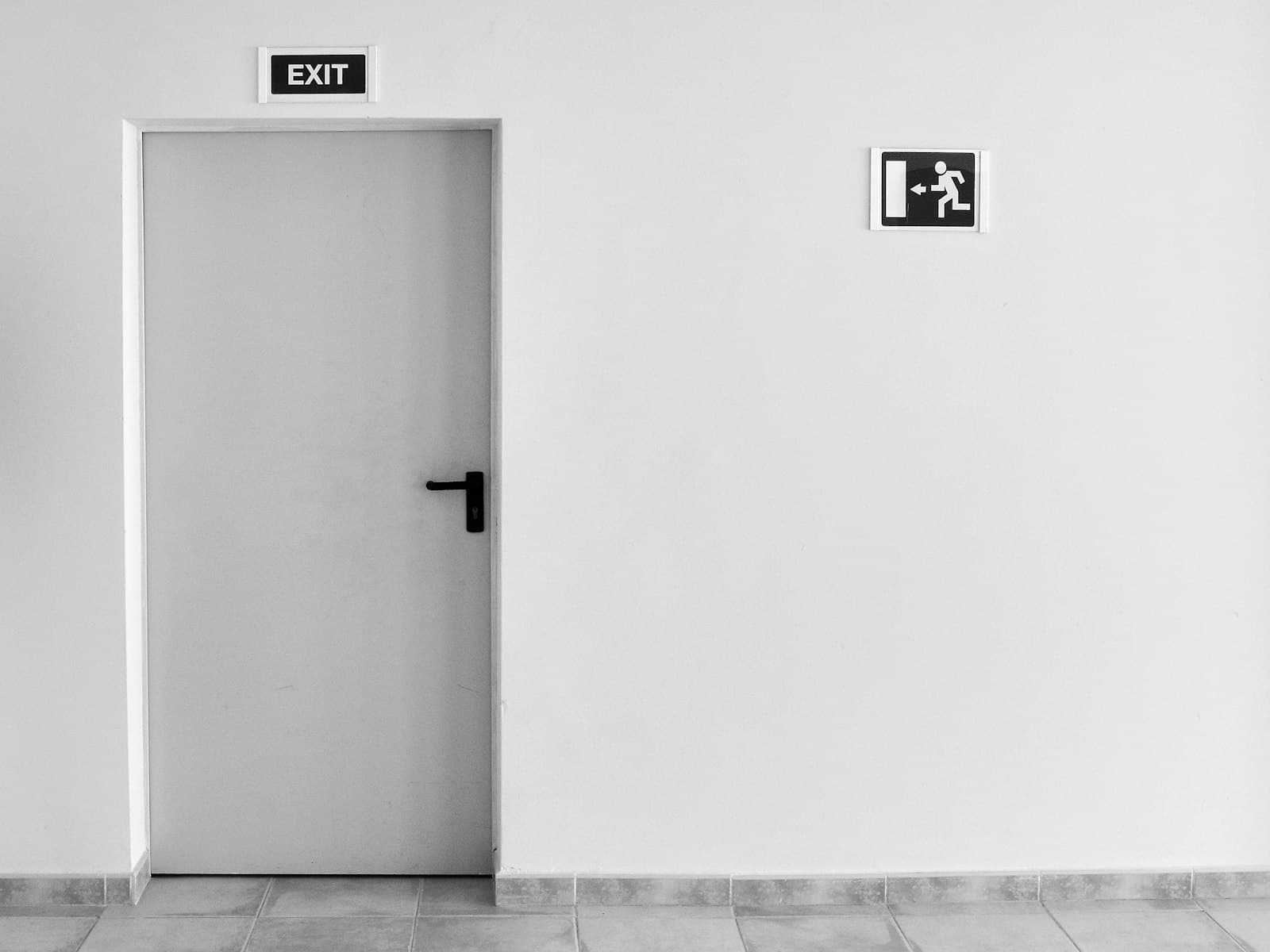 Tür in einem Rettungsweg mit Exit-Schild und Fluchtweg-Piktogramm, Foto