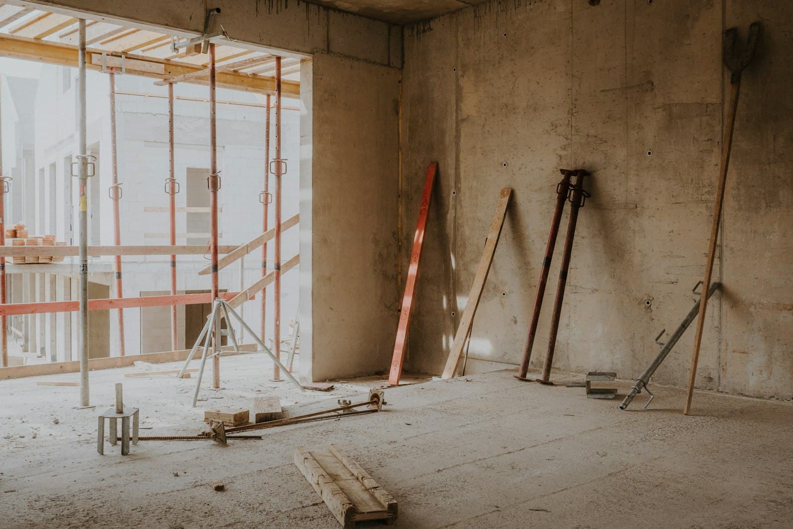 Entkerntes Geschoss mit Rohbetonwänden, Baustaub und Deckenstützen auf einer Sanierungsbaustelle, Foto